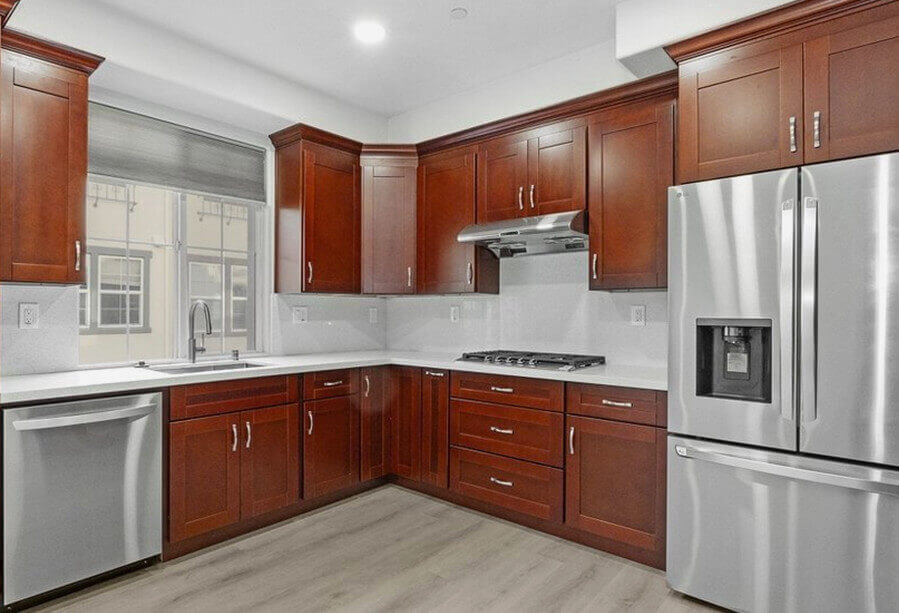 Modern kitchen featuring dark wooden cabinets, stainless steel appliances, and a spacious countertop with a sink near a window.